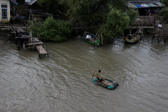 A man rows a makeshift boat to reach his house isolated by sea water at Pantai Mekar village in Bekasi, West Java province, Indonesia, January 22, 2018. (Photo by Reuters/Beawiharta)