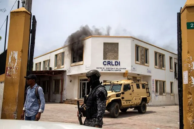 A national police officer walks in front of the National ID office that was set on fire by demonstrators during a protest by police for better working conditions and the release of jailed officers in Port-au-Prince, Haiti, Monday, September 14, 2020. The protest was called for by a nation-wide police group called “Phantom 509”, which is associated with the police union. (Photo by Dieu Nalio Chery/AP Photo)