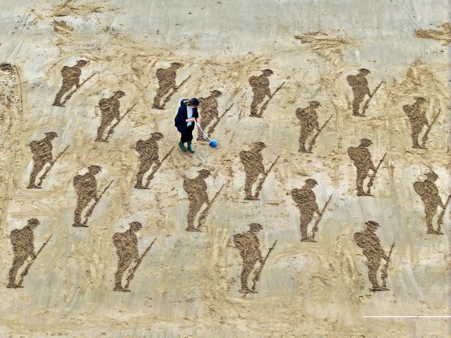 A drone view shows a member of Royal British Legion Industries (RBLI) clearing away sand on a sand artwork depicting soldiers as part of an installation erected in Stone Bay ahead of the 80th anniversary of the D-Day landings, in Broadstairs, Britain, on May 22, 2024. (Photo by Dylan Martinez/Reuters)