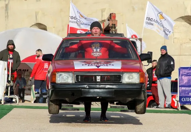 An athlete carries a body of a car during a strongmen contest “People are stronger than machines” in Sevastopol, Crimea, November 21, 2020. (Photo by Alexey Pavlishak/Reuters)