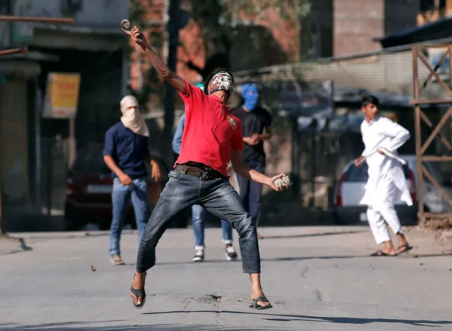 A Kashmir demonstrator hurls a stone at Indian policemen during an anti-India protest in Srinagar October 14, 2016. (Photo by Danish Ismail/Reuters)