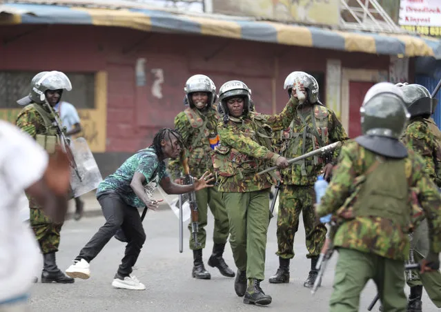 Police clash with a man during a protest by supporters of Kenya's opposition leader Raila Odinga over the high cost of living and alleged stolen presidential vote, in Nairobi, Monday, March 20, 2023. (Photo by Brian Inganga/AP Photo)