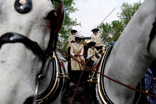 Participants wearing period dresses wait for parading in the XXXIII “Enganches” (Horse- drawn carriages) exhibition at the Real Maestranza bullring in Sevilla on April 15, 2018. (Photo by Cristina Quicler/AFP Photo)