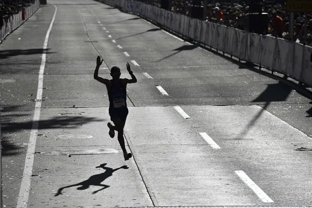 Colombian runner John Tello celebrates his fourth place before crossing the finish line of the CAF marathon in Caracas, Venezuela, Sunday, March 19, 2023. (Photo by Matias Delacroix/AP Photo)