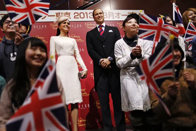 Guests wave Union Jack flags as they pose with wax figures of Britain's Prince William and his wife Catherine, Duchess of Cambridge at the Madame Tussauds Tokyo wax museum, in Tokyo November 28, 2012. (Photo by Issei Kato/Reuters)
