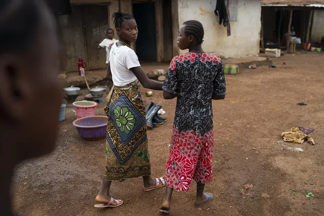 Marie walks with a friend on a street in Komao village, on the outskirts of Koidu, district of Kono, Sierra Leone, Sunday, November 22, 2020. A man, in his mid-20s, first caught a glimpse of Marie as she ran with her friends past his house near the village primary school. Soon after, he proposed to the fifth-grader. “I’m going to school now. I don’t want to get married and stay in the house”, she told him. But the pressures of a global pandemic on this remote corner of Sierra Leone were greater than the wishes of a schoolgirl. (Photo by Leo Correa/AP Photo)