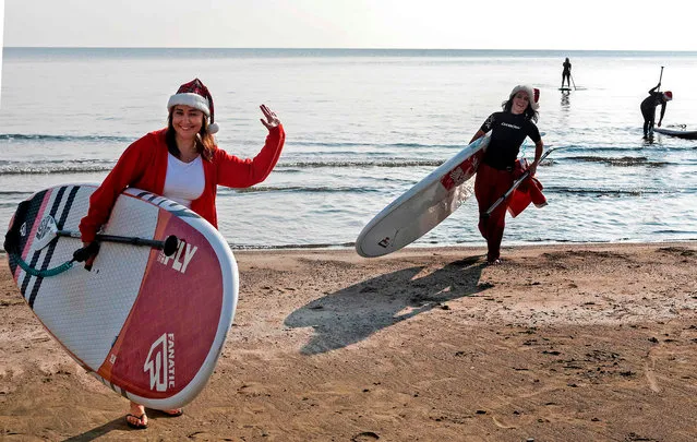Members and friends of a Cypriot surfing club, dressed as Santa Claus to celebrate the holidays, set out to sea on stand up paddle (SUP) boards at Makenzy beach, in the southern city of Larnaca, on December 23, 2020. (Photo by Iakovos Hatzistavrou/AFP Photo)