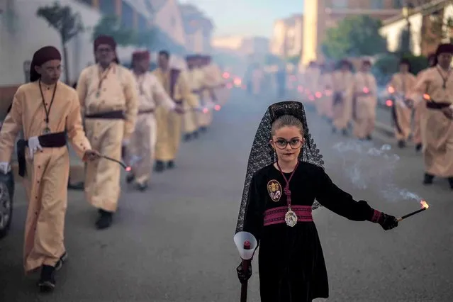 A child of the “Jesus Preso” brotherhood burns flares during the holy week procession in Moriles, southern Spain, Thursday, April 6, 2023. Hundreds of processions take place throughout Spain during the Easter Holy Week. (Photo by Manu Fernandez/AP Photo)