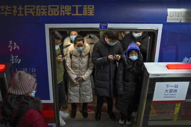 Commuters wearing face masks to help curb the spread of the coronavirus crowd inside a subway train during a rush hour in Beijing, Tuesday, January 5, 2021. Wary of another wave of infections, China is urging tens of millions of migrant workers to stay put during next month's Lunar New Year holiday, usually the world's largest annual human migration. (Photo by Andy Wong/AP Photo)