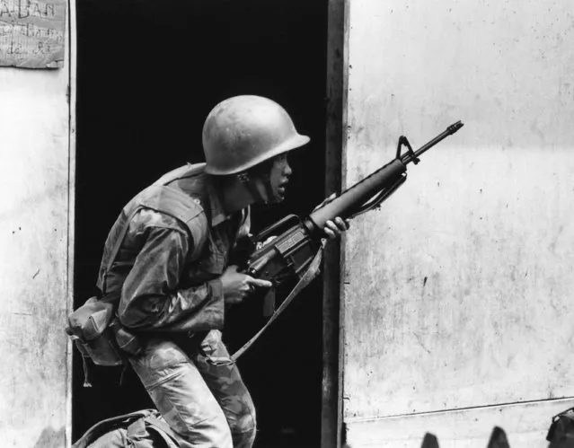 A South Vietnamese soldier, his weapon at the ready, looks out of a doorway in Saigon on May 9, 1968 to see from which spot Viet Cong snipers are firing. (Photo by John T. Wheeler/AP Photo)
