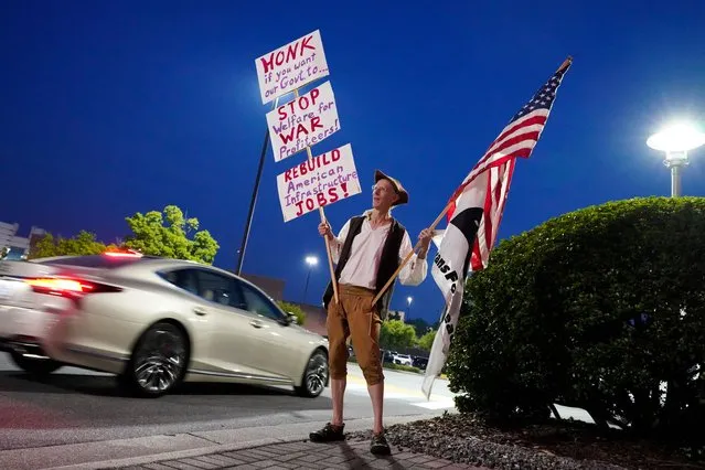 Roger Ehrlich, of Veterans for Peace, holds signs as cars pass by after former President Donald Trump spoke at the North Carolina Republican Party Convention in Greensboro, N.C., Saturday, June 10, 2023. (Photo by George Walker IV/AP Photo)