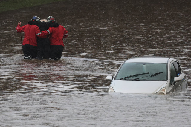 Firefighters rescue a man from his car, after he became trapped in flood water on the A555 near Bramhall, Britain, on January 1, 2025. (Photo by Phil Noble/Reuters)