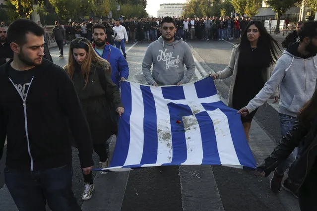 University students hold a blood-stained Greek flag from the deadly 1973 student uprising in Athens, Thursday, November 17, 2016. Several thousand people marched to the U.S. Embassy in Athens under tight police security to commemorate a 1973 student uprising that was crushed by Greece's military junta, that ruled the country from 1967-74. (Photo by Yorgos Karahalis/AP Photo)