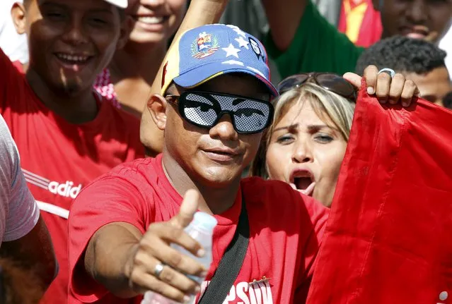 A supporter of Venezuela's President Nicolas Maduro, wearing glasses with the eyes of Venezuela's late President Hugo Chavez, gestures as he gathers with others some streets away from the building housing the National Assembly in Caracas, January 5, 2016. (Photo by Christian Veron/Reuters)