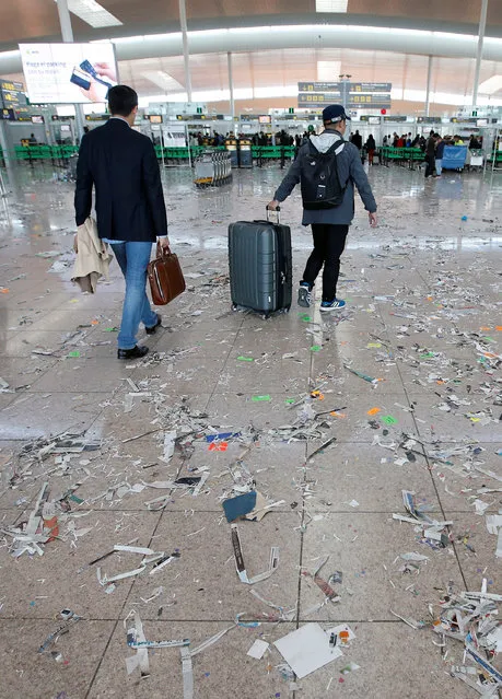 Passengers pull their suitcases as the floor is littered with pieces of paper during a protest by the cleaning staff at Barcelona's airport, Spain, December 1, 2016. (Photo by Albert Gea/Reuters)