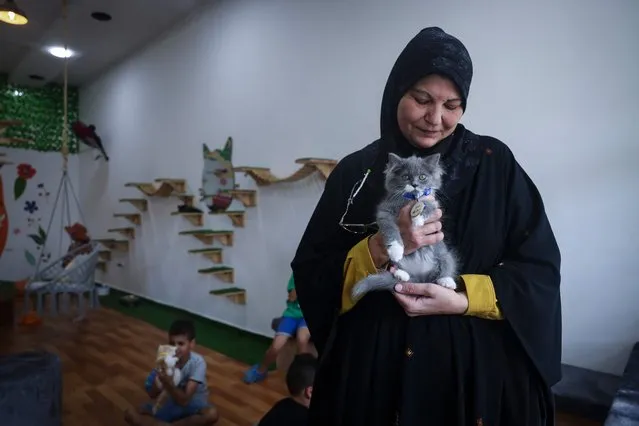 A woman holds a feline at the newly inaugurated Cat Cafe in Gaza City on August 17, 2023. (Photo by Mohammed Abed/AFP Photo)