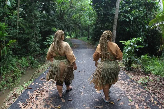People of Mah Meri tribe walking to pray house at Pulau Carey village on December 03, 2016 in Selangor, Malaysia. The Mah Meri people are one 18 tribes of Orang Asal (indigenous people) living in west Malaysia. The Mah Meri are know for thei wood carvings and also for the richness of their songs and dances. One of the most well-known dances of the the Mah Meri peole is the mask dance, called Mayin Jo-ah-a traditional dance perforfmed to invite the ancestral spirits, or Muyang, to join in the festivity. In this dance, the performers wear grotesque masks and perform with movements and gestures to relate everyday events such as fishing and celebrations. The mask worn in the Mah Meri Mask Dance depict the spirits of birds and other animals that inhabit the Mah meri's sorrounding, such as the swamp and the sea. The female dancers wear skirts of “mengkuang” leaves and plaited “mengkuang” head dress. The female performers dance anti-clockwise around an earthen mound, called a busot, while the male masked dancers performed clockwise around the women. The dance is performed accompained by the music from the tuntog (bamboo stampers), jule (viola), tambo (double-heade drum) and a-tawa (brass gong). (Photo by Yuli Seperi/Sijori Images/Barcroft India)