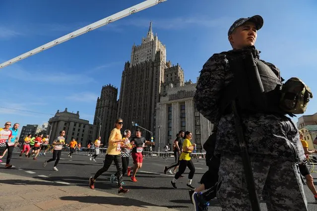 A law enforcement officer looks on as runners take part in the annual Moscow Marathon in the centre of Moscow on September 17, 2023. (Photo by Handout/Moskva News Agency via AFP Photo)