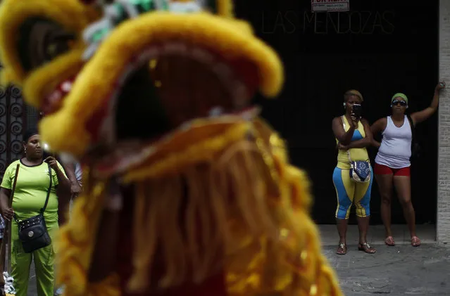 Bystanders watch as dancers perform a lion dance outside a local shop during celebrations of the Chinese Lunar New Year of the Monkey in Chinatown in Panama City, Panama February 8, 2016. (Photo by Carlos Jasso/Reuters)