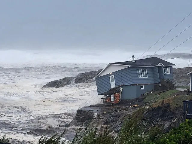 In this photo provided by Wreckhouse Press a home fights against high winds caused by post Tropical Storm Fiona in Port aux Basques, Newfoundland and Labrador, Saturday, September 24, 2022. The home has since been lost at sea. (Photo by Rene Roy/Wreckhouse Press via The Canadian Press via AP Photo)