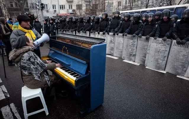 Protestors sing and play a piano decorated with EU and Ukrainian symbols as Interior Ministry members stand guard near the presidential administration building during a rally held by supporters of EU integration in Kiev, on December 7, 2013. (Photo by Reuters)