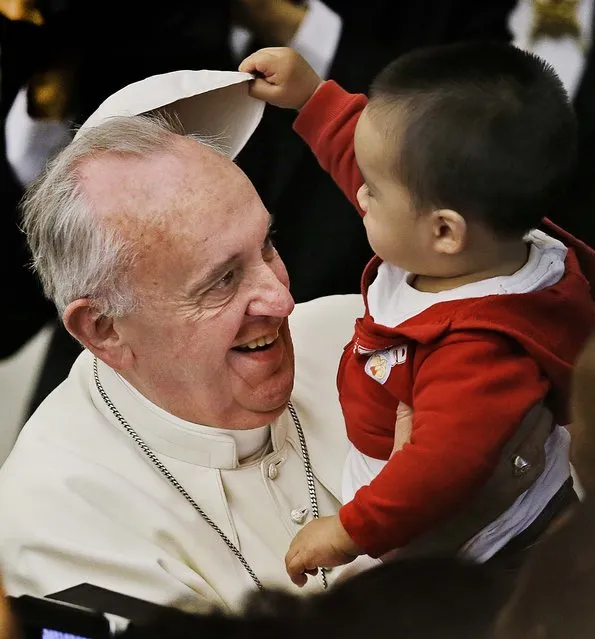 A child takes off Pope Francis' white zucchetto, or skullcap, during a meeting with children and volunteers of the Santa Marta Vatican Institute, at the Vatican, on December 14, 2013. (Photo by Gregorio Borgia/Associated Press)