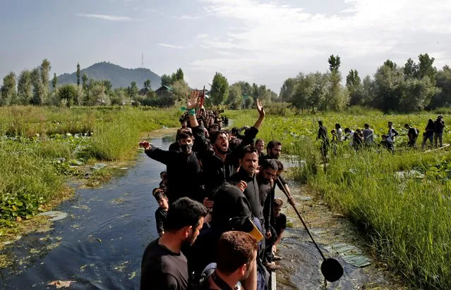 Kashmiri Shi'ite Muslims shout religious slogans as they ride on boats in the interiors of Dal Lake during a Muharram procession ahead of Ashura in Srinagar August 18, 2021. (Photo by Danish Ismail/Reuters)