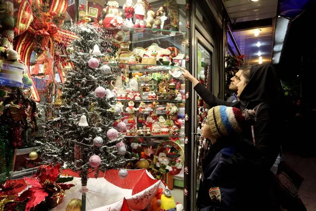 An Iranian family look at the window of a shop selling Christmas ornaments in Tehran on December 24, 2013, as Christians around the world prepare for Christmas celebrations. (Photo by Atta Kenare/AFP Photo)