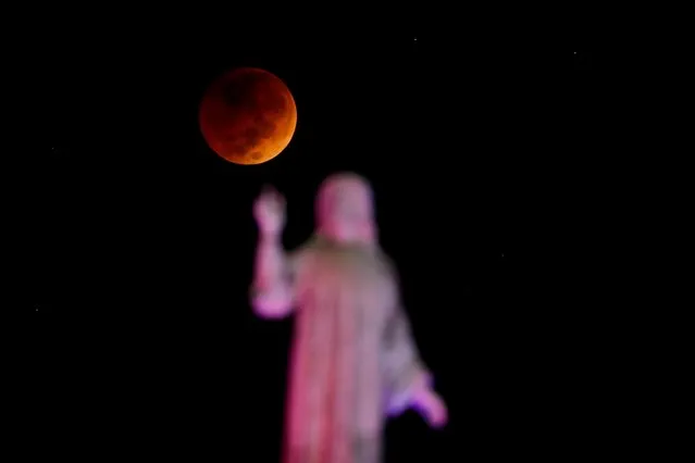 The moon and a statue are seen during a lunar eclipse in San Salvador, El Salvador on November 8, 2022. (Photo by Jose Cabezas/Reuters)