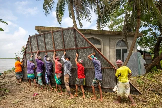 Laborers carry parts of a damaged house as the erosion of the River Padma continues washing away concrete structures at Tongibari, Munshiganj district outskirts of Dhaka, Bangladesh, 27 August 2021. According to the UNICEF report Bangladesh ranks second among South Asian countries where children are at extremely high risk of the impacts of the climate crisis, 15th globally in UNICEF’s index. (Photo by Monirul Alam/EPA/EFE)