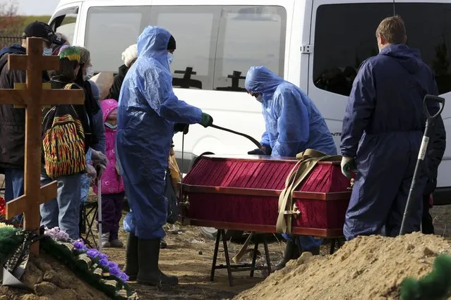Grave diggers wearing protective suits disinfect a coffin of a COVID-19 victim for burial at a cemetery outside Omsk, Russia, Thursday, October 7, 2021. Russia's daily coronavirus infections have soared to their highest level so far this year as authorities have struggled to control a surge in new cases amid a slow pace in vaccinations and few restrictions in place. The daily coronavirus death toll topped 900 for a second straight day with 924 new deaths reported Thursday. Russia already has Europe's highest death toll in the pandemic and a conservative way of calculating the number suggests the actual number could be even higher. (Photo by AP Photo/Stringer)
