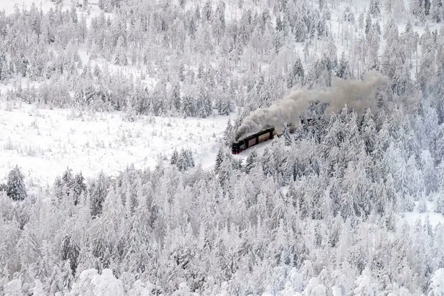 A steam train travels through a snow covered landscape on the way to northern Germany's 1,142-meter (3,743 feet) highest mountain “Brocken” at the Harz mountains near Schierke, Germany, Wednesday, January 17, 2024. (Photo by Matthias Schrader/AP Photo)