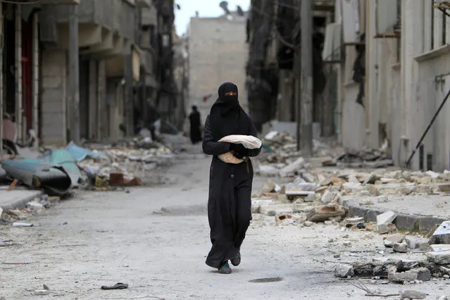 A woman carries bread through a damaged street in Aleppo, Syria January 30, 2017. (Photo by Ali Hashisho/Reuters)