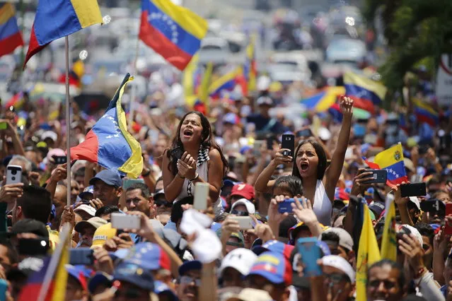 In this Saturday, March 16, 2019 photo, people cheer for Venezuelan opposition leader Juan Guaido, who declared himself interim president, at a rally in Valencia, Venezuela. Large crowds gathered in the northern Venezuelan city to greet Guaido, who plans to tour the country as part of his campaign to oust President Nicolas Maduro. (Photo by Fernando Llano/AP Photo)