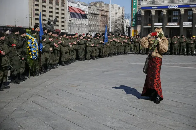 A woman takes pictures as members of a Ukrainian National Guard battalion named after General Serhiy Kulchytsky take part in a ceremony in honour of the second anniversary of the battalion's creation and to commemorate members killed in the pro-Russian separatist conflict in eastern regions, in Kiev, Ukraine, March 16, 2016. (Photo by Gleb Garanich/Reuters)