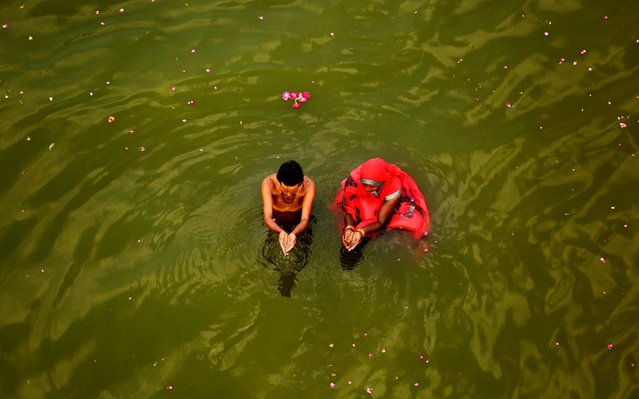 A couple performs morning rituals in the River Ganges on the first day of the nine-day Hindu festival of Navratri on the outskirts of Prayagraj , in the northern Indian state of Uttar Pradesh, India, Saturday, April 6, 2019. Hindus are celebrating Navaratri, or the festival of nine nights, with three days each devoted to the worship of Durga, the goddess of valor, Lakshmi, the goddess of wealth, and Saraswati, the goddess of knowledge. (Photo by Rajesh Kumar Singh/AP Photo)