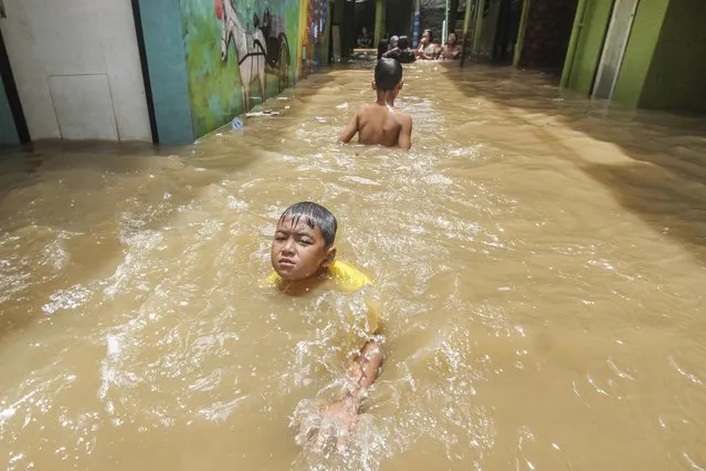 Children play on water after flood hit their home at Kebon Pala area, Jakarta, Indonesia on November 8, 2021. The high intensity of rainfall has resulted in a number of settlements on the Ciliwung river area being submerged by floods as high as 1.5 to 2 meters. (Photo by Eko Siswono Toyudho/Anadolu Agency via Getty Images)