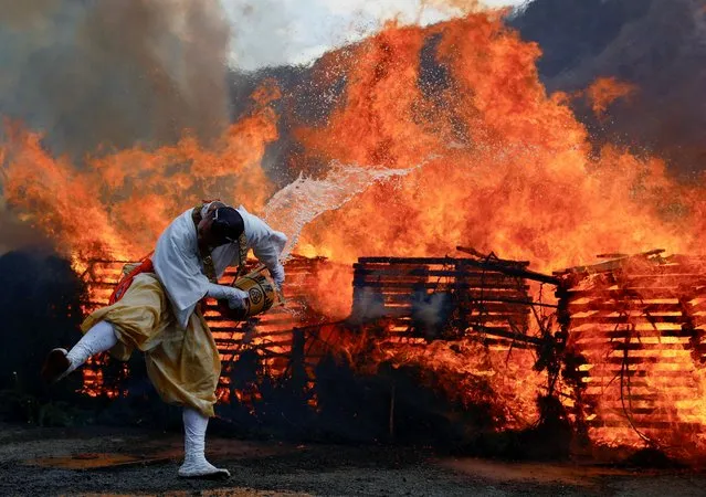 A Buddhist monk splashes water on a bonfire at the fire-walking festival, called Hiwatari Matsuri in Japanese, at Mt.Takao in Tokyo, Japan on March 10, 2024. Over 1,000 worshipers walk barefoot with Buddhist monks over coals at the annual festival, praying for their safety and peace in the world, according to the organiser Takao-san Yakuo-in Buddhist temple. (Photo by Issei Kato/Reuters)