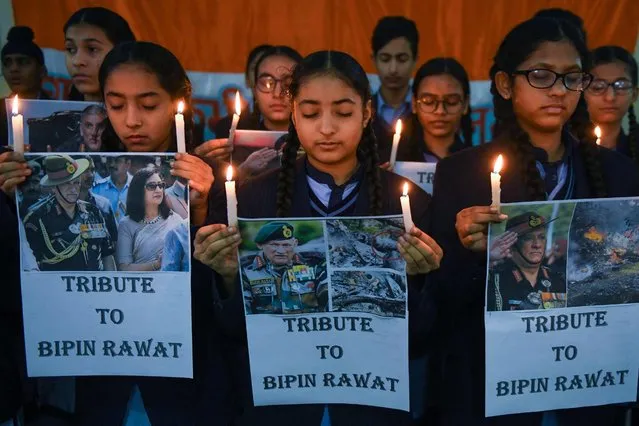 Students hold light candles and posters to pay their tribute to India's defense chief General Bipin Rawat, who was killed with 13 others a day earlier in a helicopter crash, at their school in Amritsar on December 9, 2021. (Photo by Narinder Nanu/AFP Photo)