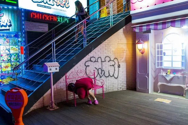 A woman leans over as she sits on a bench in the trendy nightlife district of Hongdae in Seoul, May 9, 2015. (Photo by Thomas Peter/Reuters)