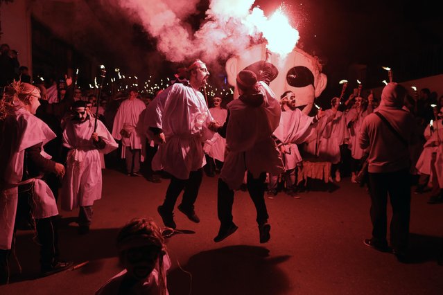 In this photo taken on Saturday, February 25, 2017 two men sing and dance during the Torch Parade on the Greek island of Naxos. (Photo by Thanassis Stavrakis/AP Photo)