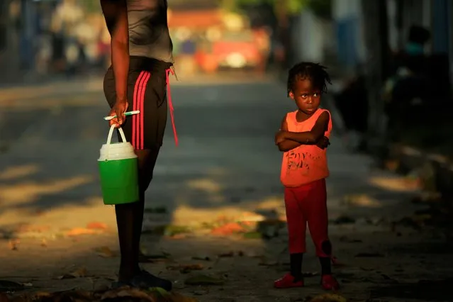A Haitian girl and her mother wait to wash, as they take part in a caravan to the U.S. border, in Mapastepec, Mexico on November 23, 2021. (Photo by Jose Luis Gonzalez/Reuters)