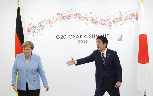 Japanese Prime Minister Shinzo Abe, right, and German Chancellor Angela Merkel, left, gesture at their bilateral meeting prior to the G-20 summit in Osaka, Japan, Friday, June 28, 2019. (Photo by Eugene Hoshiko/Pool via Reuters)