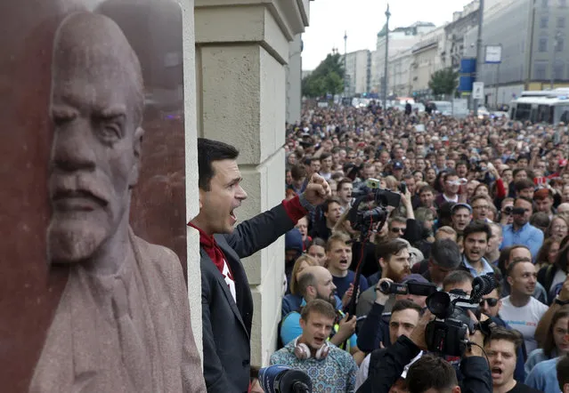 Russian opposition candidate Russian and activist Ilya Yashin, center, gestures while speaking to a crowd next to a bas-relief of the Soviet founder Vladimir Lenin, left, during a protest in Moscow, Russia, Sunday, July 14, 2019. Opposition candidates who run for seats in the city legislature in September's elections have complained that authorities try to bar them from the race by questioning the validity of signatures of city residents they must collect in order to qualify for the race. (Photo by Pavel Golovkin/AP Photo)