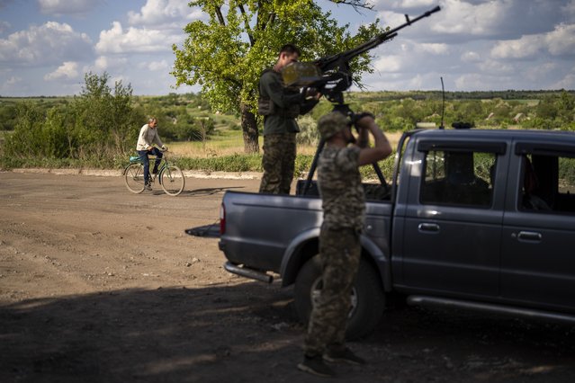 A local resident rides a bicycle past an Ukrainian army anti-drone unit, in Avdiivka direction, Ukraine, Monday, May 6, 2024. (Photo by Francisco Seco/AP Photo)