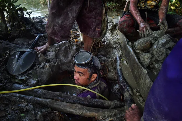 Christian Balderosdasco, 31, is being pulled up a mud pit after diving for 3 hours to look for gold on March 22, 2017 in Paracale, Philippines. (Photo by Jes Aznar/Getty Images)