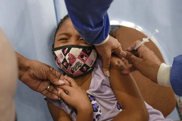 A child gets her first shot of the Sinopharm COVID-19 vaccine during a vaccination campaign at Alba Caracas's hotel in Caracas, Venezuela, Monday, January 3, 2022. (Photo by Matias Delacroix/AP Photo)