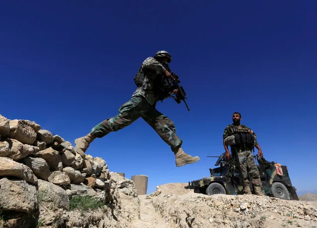 A member of Afghanistan's Special Forces unit jumps from a wall during patrol in Pandola village near the site of a U.S. bombing in the Achin district of Nangarhar, eastern Afghanistan, April 14, 2017. (Photo by Reuters/Parwiz)