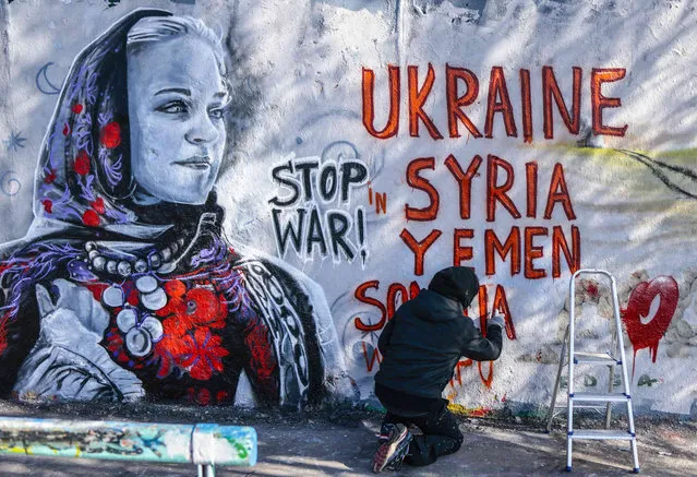 Berlin-based Colombian street artist Arte Vilu works on a mural featuring a Ukrainian woman in traditional dress in Berlin, Germany, Monday, Feb. 28, 2022. On Thursday, February 24, 2022 Russian troops have launched their anticipated attack on Ukraine. (Photo by Hannibal Hanschke/AP Photo)