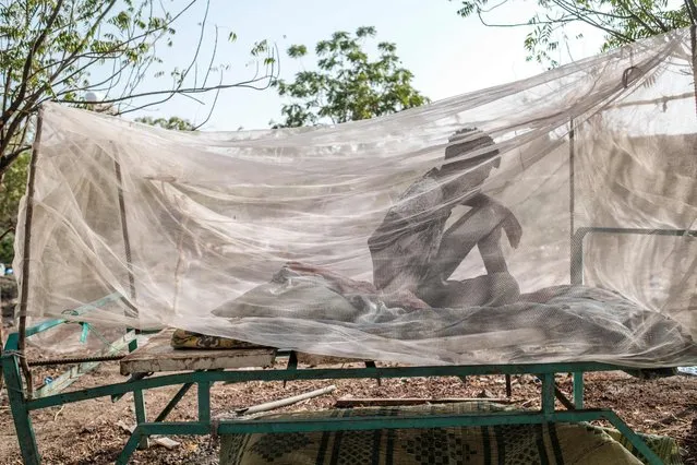 A civilian man fleeing violence seats in a bed covered with a mosquito net at the compound of the Agda Hotel, in the city of Semera, Ethiopia, on February 17, 2022. Thousands of Eritrean refugees, shell-shocked and separated from loved ones, fled on foot through harsh terrain to escape artillery and gunfire. (Photo by Eduardo Soteras/AFP Photo)